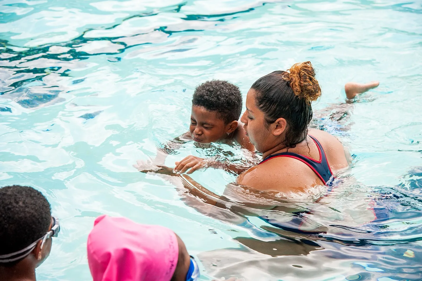 Pelatih renang membimbing anak belajar berenang di kolam