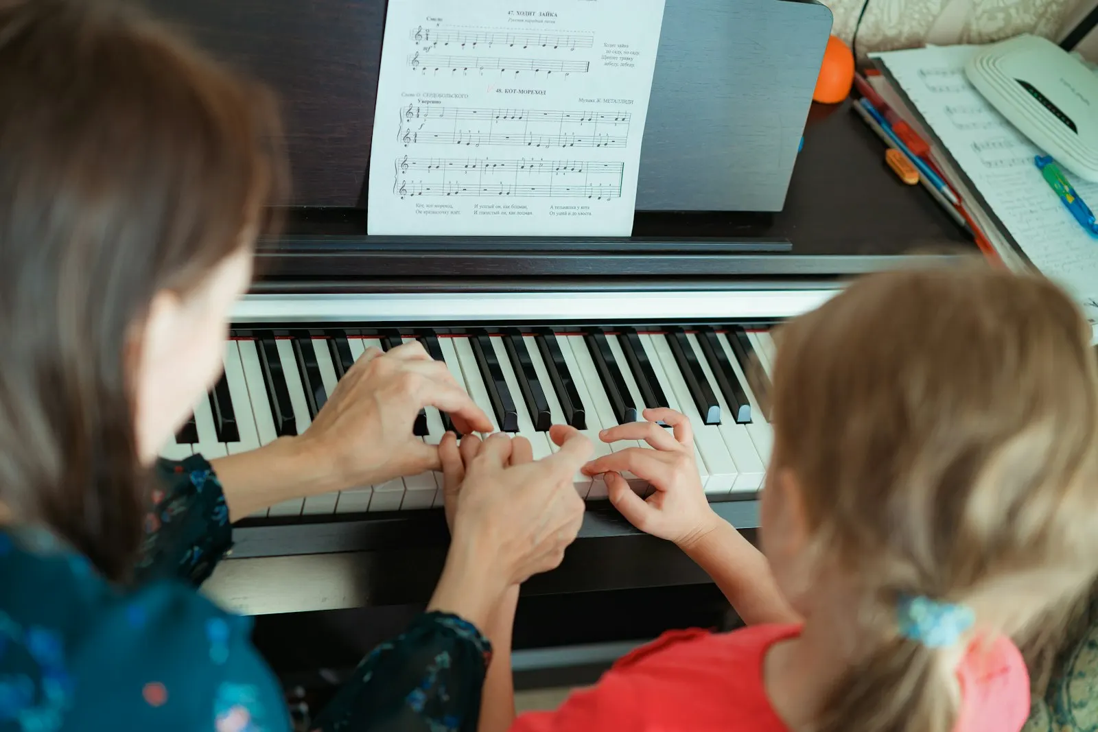 Guru dan anak perempuan bermain piano bersama